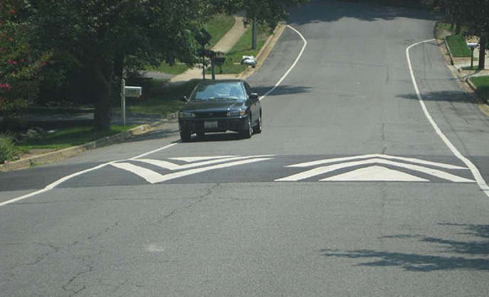 Car approaches speed hump on a roadway